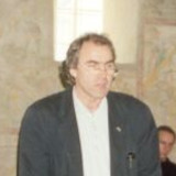 Hermann Nehls bei seiner Rede, im Hintergrund Wand und Fenster einer Kirche